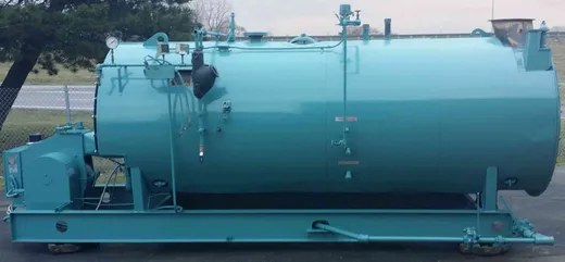 Side view of a refurbished firetube steam boiler on a steel skid, trimmed with gauge glass and controls