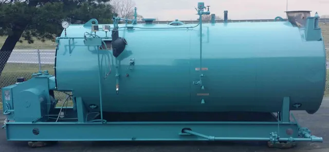 Side view of a refurbished firetube steam boiler on a steel skid, trimmed with gauge glass and controls