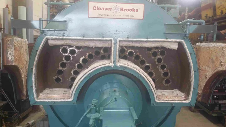 Cleaver-Brooks firetube boiler opened at the front head, exposing the tube sheet during a retube