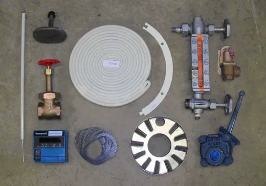 Boiler parts laid out in the shop — gate valve, water column, burner control, gaskets and rope