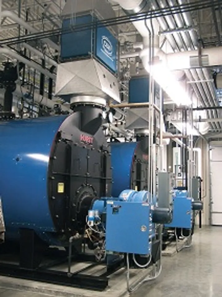 Two blue commercial firetube boilers with burners and gas piping in a mechanical room
