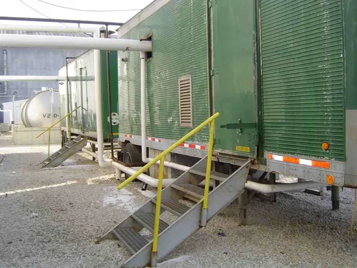 Green mobile boiler-room rental units set up and piped in at a customer plant