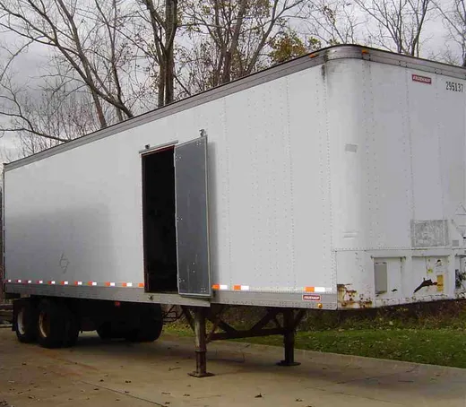 White trailer-mounted mobile boiler room parked with its access door open
